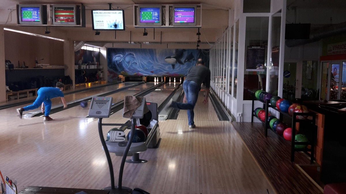 Hráč hádže bowlingovú guľu na osvetlenej dráhe